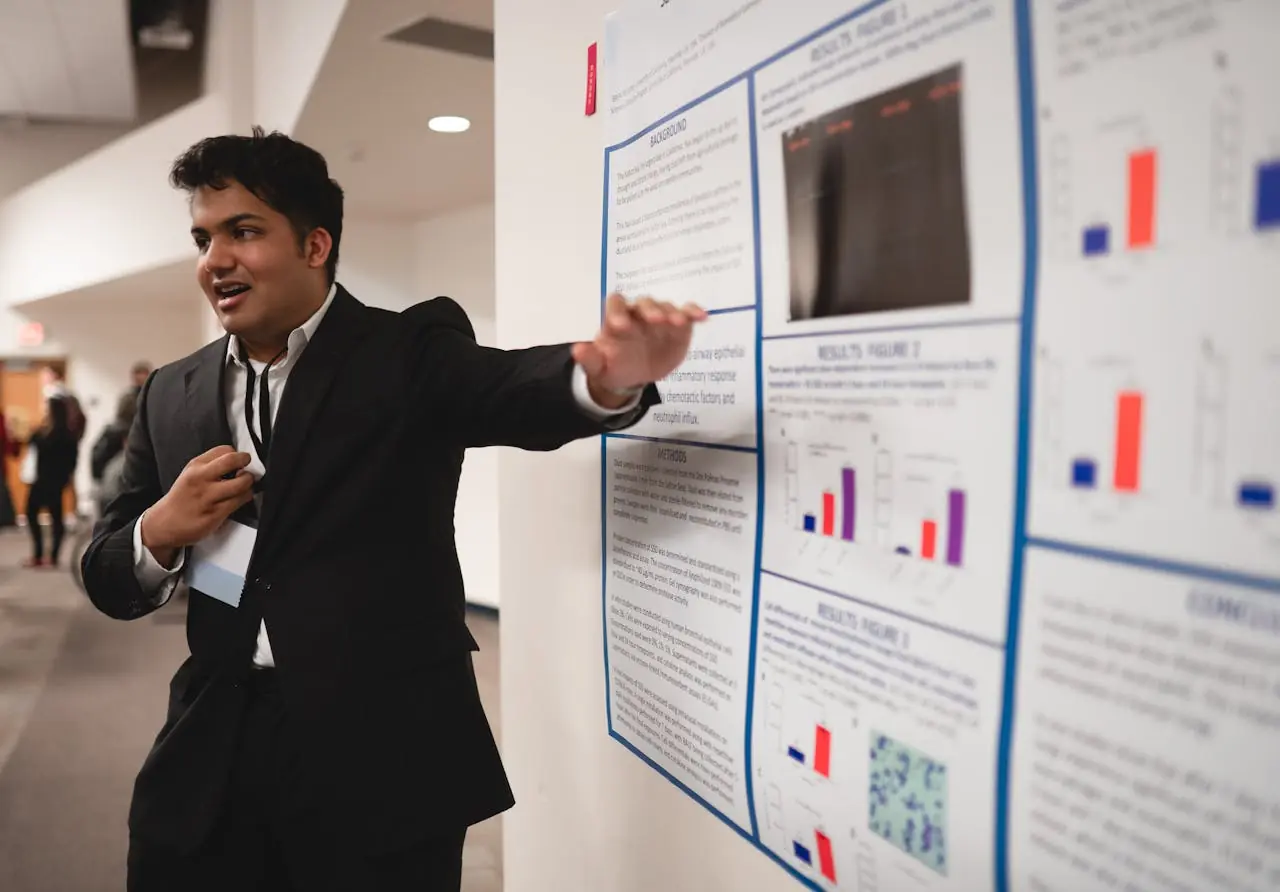 Presenter standing beside his research poster during a poster session.